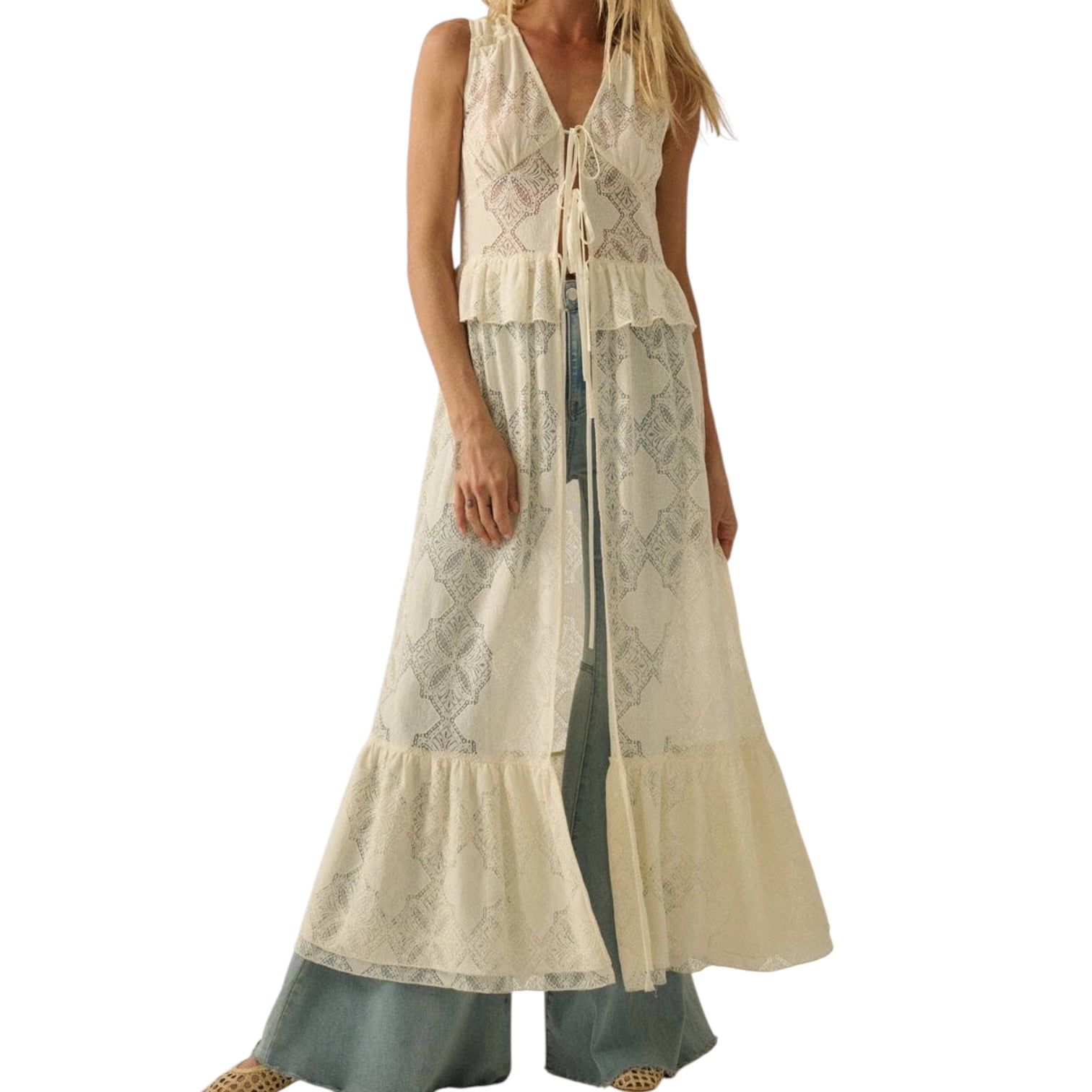 Woman wearing a long beige top over denim on a white background