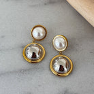 Pair of gold and pearl earrings on a gray surface