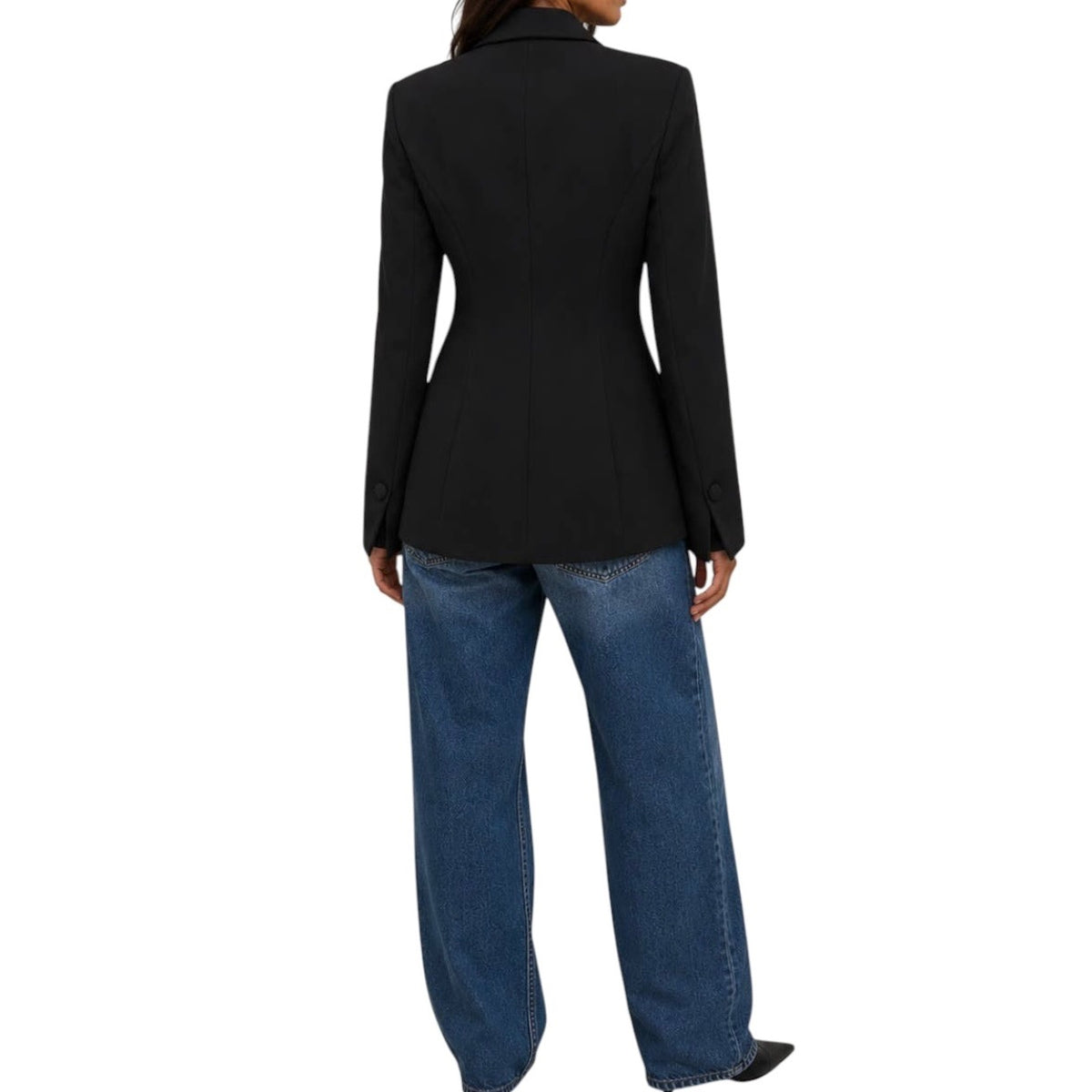 A woman shown from the back wearing a black tailored blazer and blue jeans against a plain white studio background.