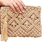 Woven clutch bag with a tassel held by a hand on a white background