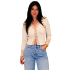 A woman modeling a cream-colored knit cardigan with textured vertical stripes down the front, paired with light-wash blue jeans, against a plain white background.