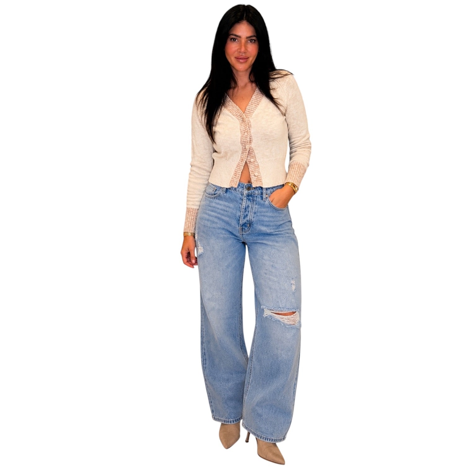 A woman modeling a light beige knit cardigan with lace trim over a white top, paired with light-wash distressed wide-leg jeans and beige heels, against a plain white background.