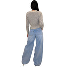 A woman shown from the back wearing a light gray marled knit long-sleeve crop top and wide-leg light blue denim jeans, set against a plain white background.
