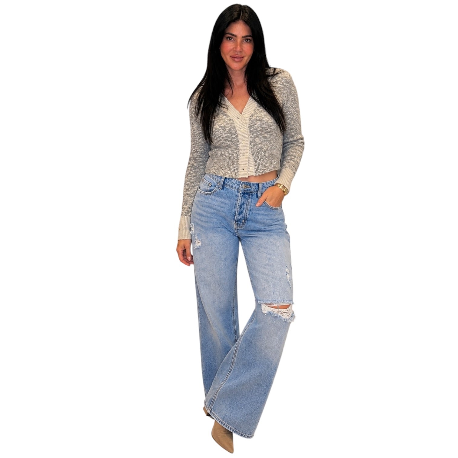 A woman modeling a light gray and white patterned long-sleeve crop top paired with light-wash, wide-leg distressed jeans, shown against a plain white background.