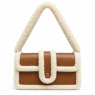 A structured shoulder bag with a smooth brown faux-leather body and thick cream sherpa fleece trim and handle, featuring a front flap pocket with a gold-tone snap button.