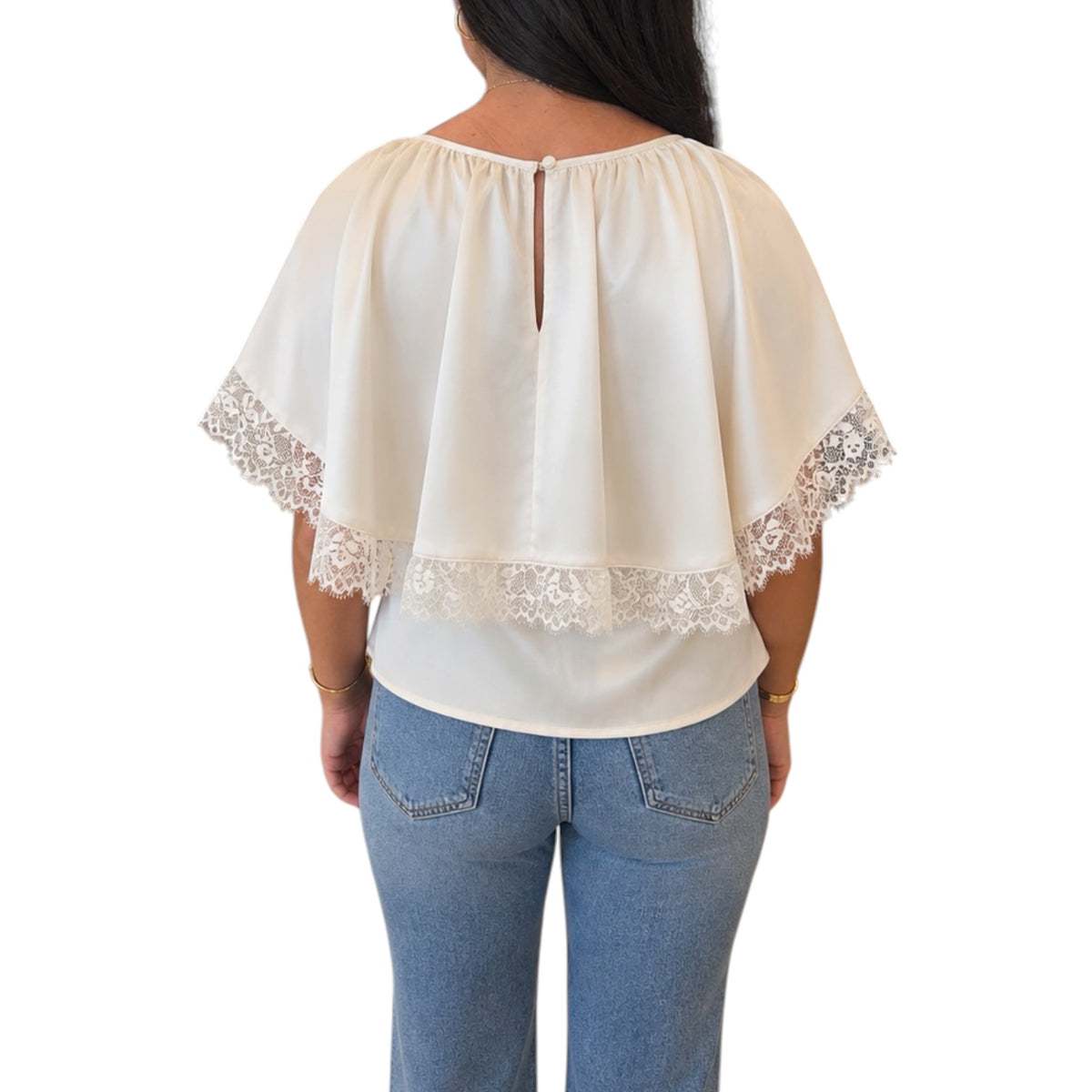 A woman viewed from the back wearing a cream-colored short-sleeve blouse with lace trim and light blue jeans, set against a plain white background.