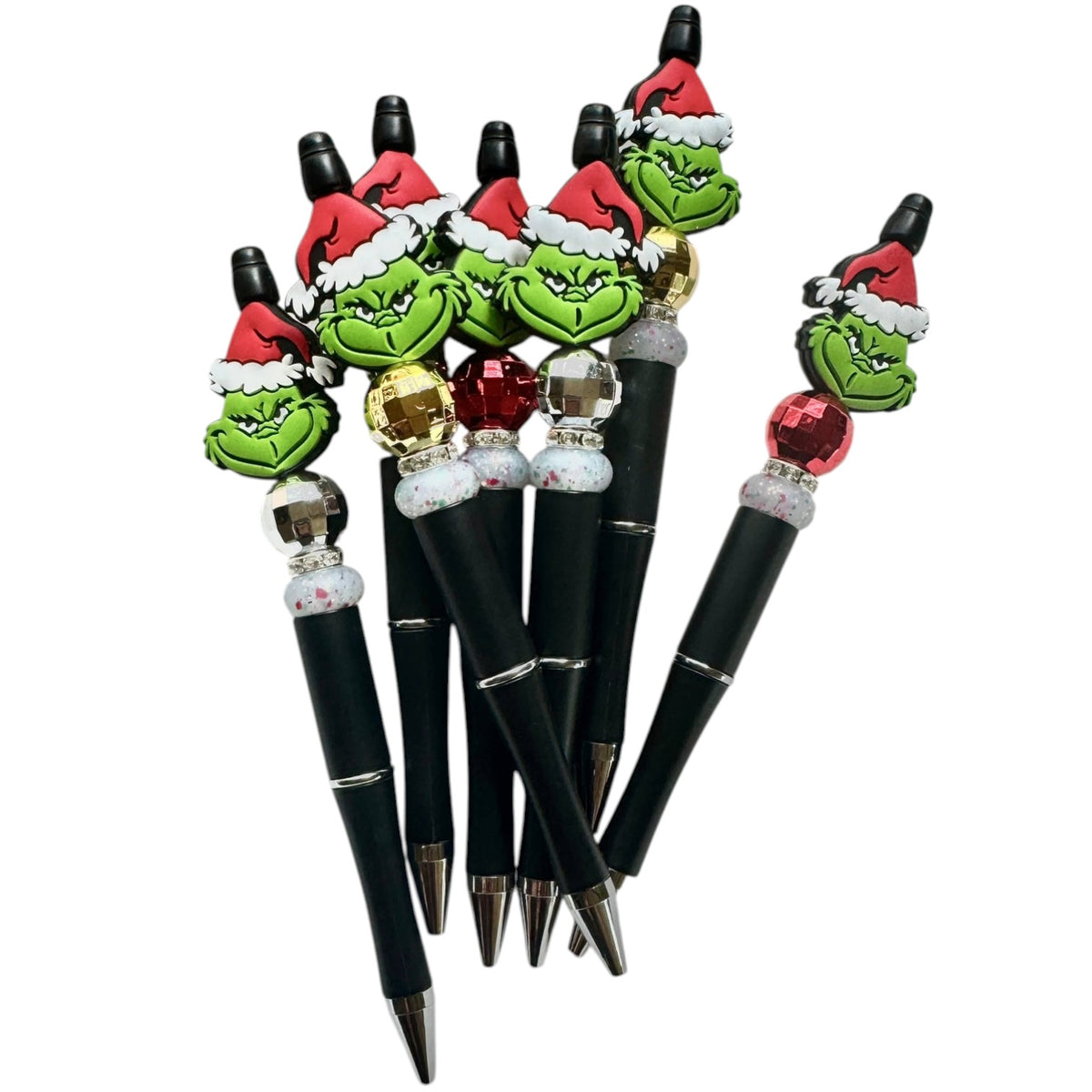 Set of pens with Grinch-themed tops on a white background