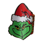 A Grinch-shaped Christmas ornament or pin featuring the Grinch's green face, yellow eyes, and an angry expression while wearing a red Santa hat with white trim, shown on a plain white background.