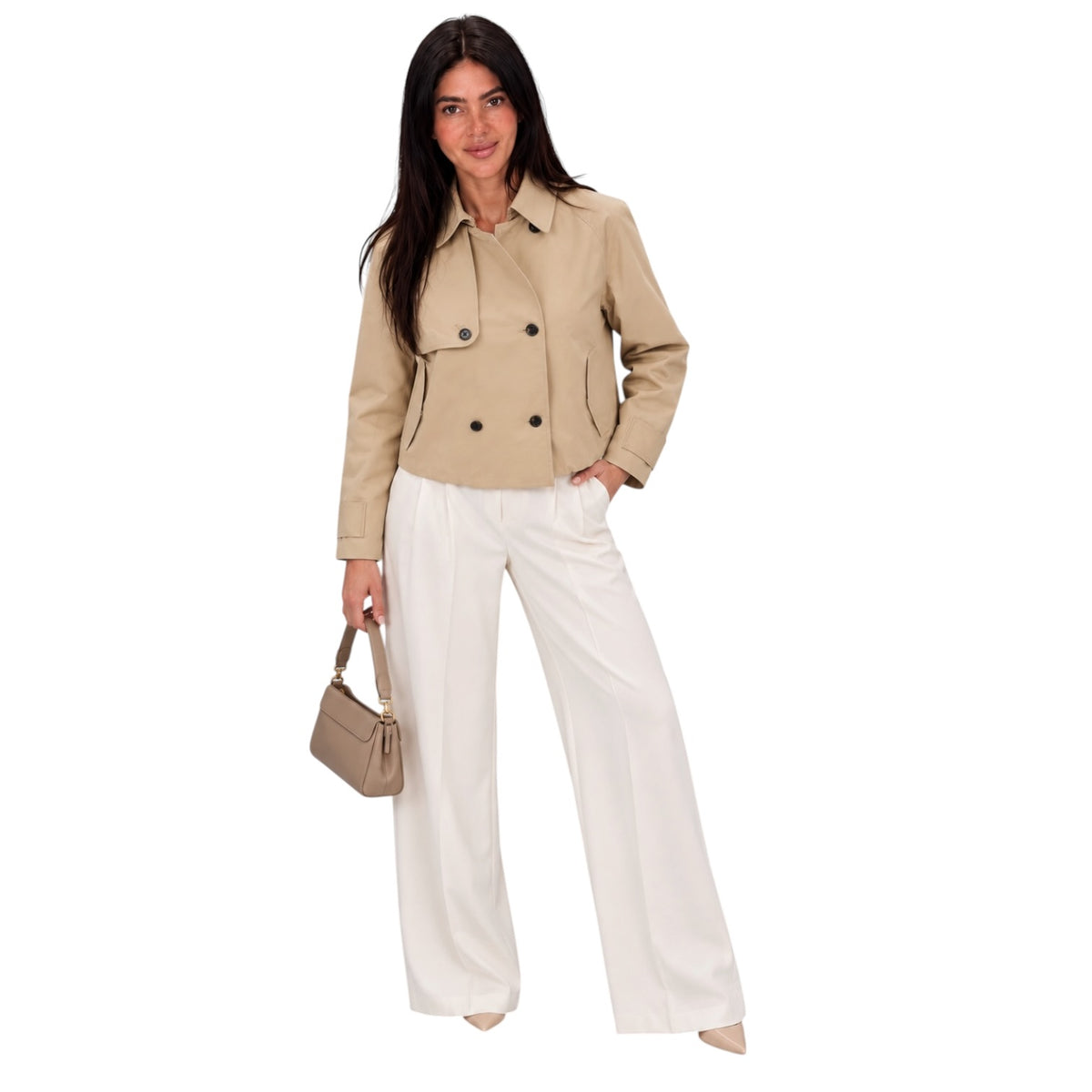 A woman modeling a beige double-breasted jacket and white wide-leg trousers, holding a beige handbag against a plain white background.