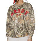 A woman wearing a camouflage crewneck sweatshirt with 'MERRY' and a bow graphic printed in red across the chest, set against a plain white background.