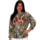 A woman modeling a long-sleeve crewneck sweatshirt with a woodland camouflage pattern and 'MERRY' printed in red across the chest.
