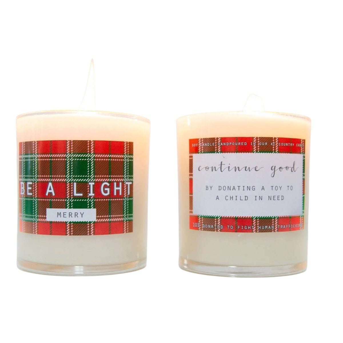 Two lit white pillar candles in clear glass holders with holiday-themed labels. The left candle has a red and green tartan label reading 'BE A LIGHT' and 'MERRY'.