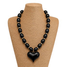 Black beaded necklace with a heart pendant on a mannequin bust.