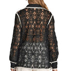 Woman wearing a black lace top and white shorts on a plain background