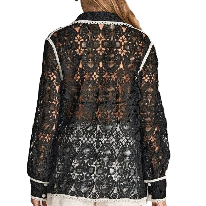 Woman wearing a black lace top and white shorts on a plain background