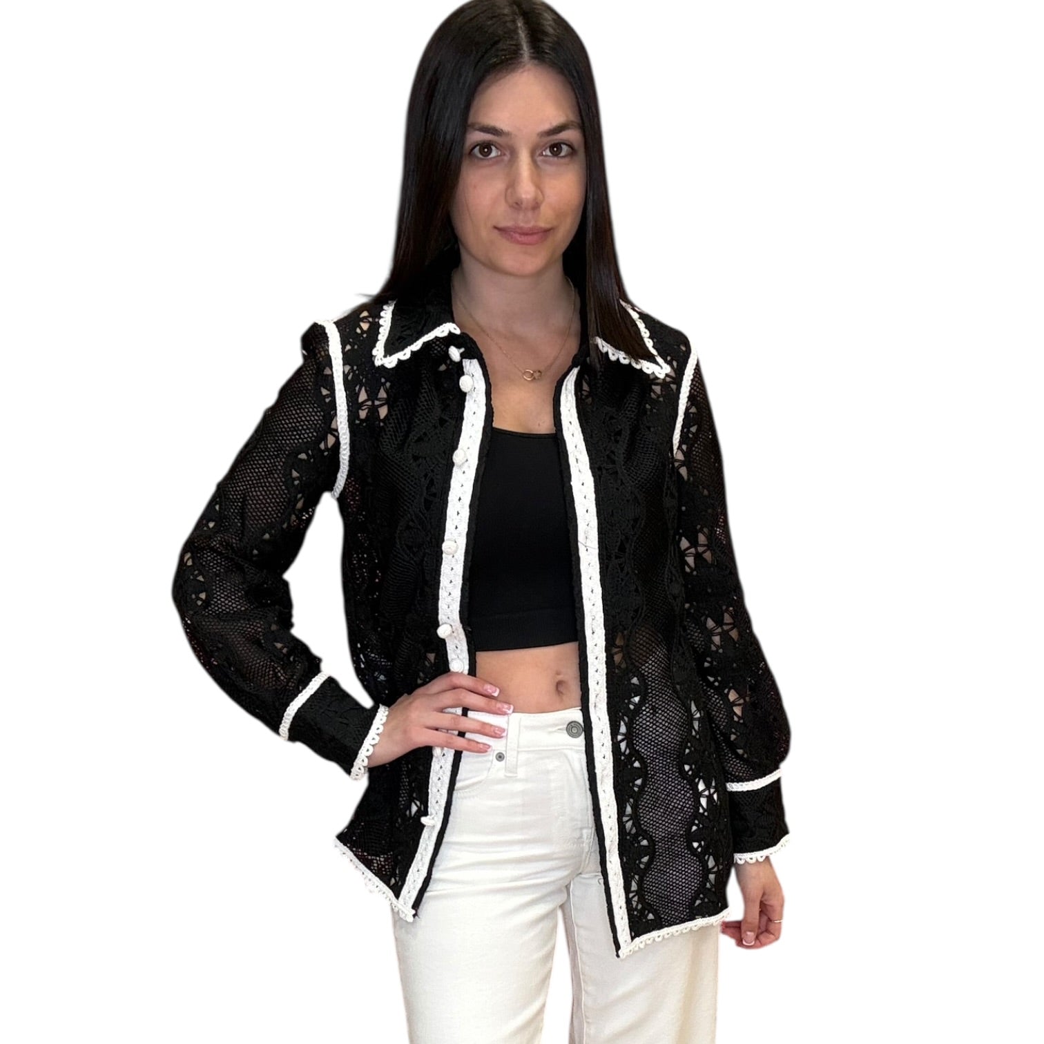 Woman wearing a black lace jacket with white trim on a white background