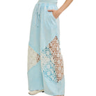 Light blue pants with lace detailing on a white background