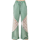Green pants with lace detailing on a white background