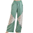 Green pants with lace detailing on a white background