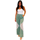 Woman wearing a white top and green pants with lace details on a white background
