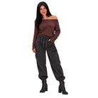 A woman modeling a dark brown off-the-shoulder long-sleeve top and dark gray baggy cargo jogger pants with black lace-up ankle boots, set against a plain white background.
