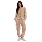 A woman modeling a beige knit loungewear set consisting of a cropped hoodie and matching cargo joggers, styled with white sneakers against a plain white background.
