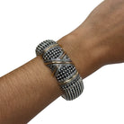 A wide silver-toned cuff bracelet with textured bead rows and gold-toned accent bands, shown worn on a person's wrist against a plain white background.