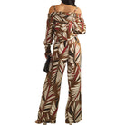 a woman wearing a palm printed two piece pant set on white background