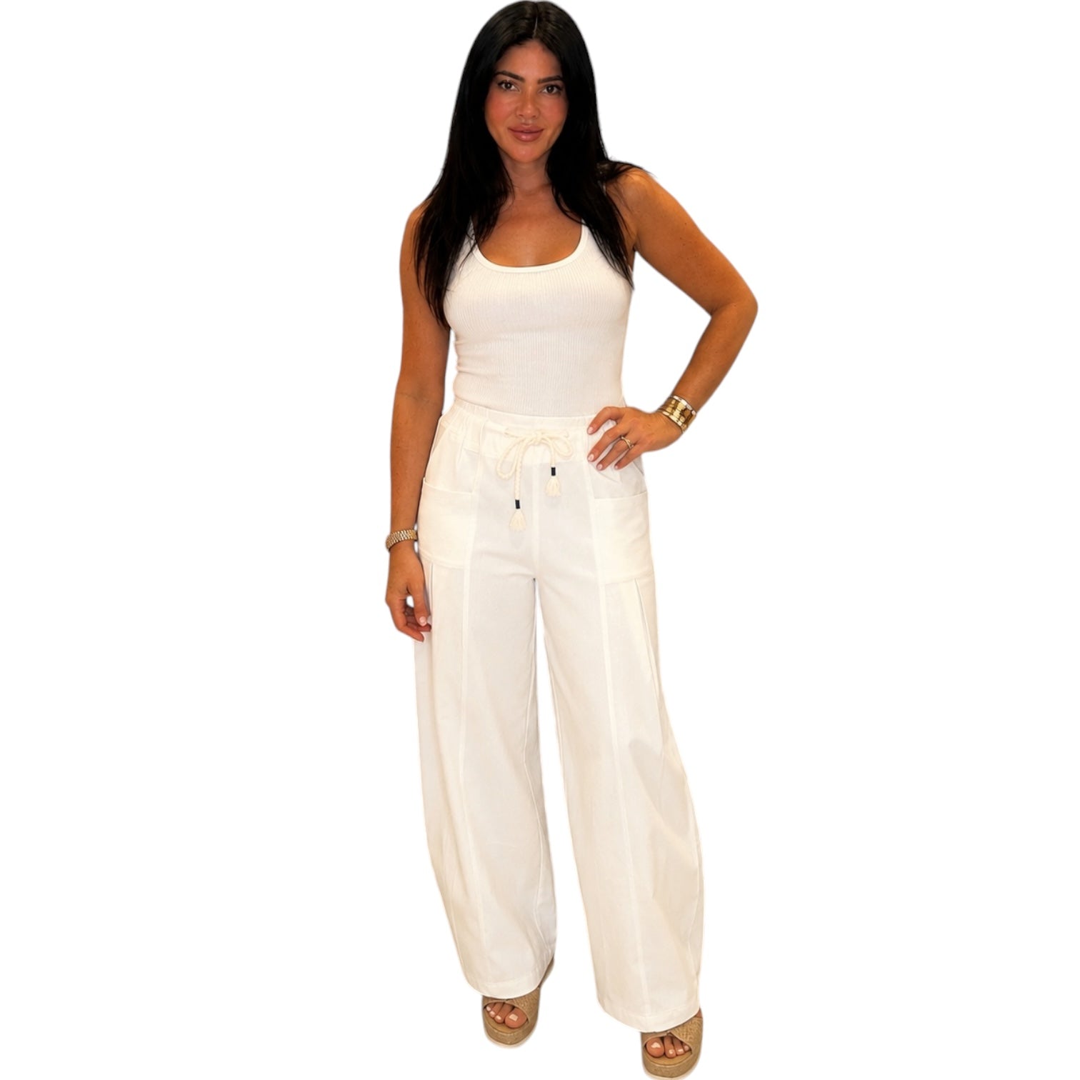 Woman wearing a white sleeveless top and wide-leg pants on a white background