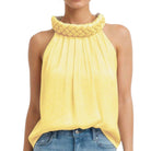 Yellow sleeveless top with textured collar worn by a person on a white background