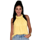 Woman wearing a yellow halter top and blue jeans on a white background