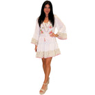 Woman wearing a white embroidered dress on a white background