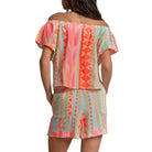 Woman wearing a colorful off-shoulder dress with geometric pattern on a white background