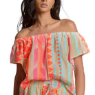 Woman wearing a colorful off-shoulder top with geometric patterns on a white background