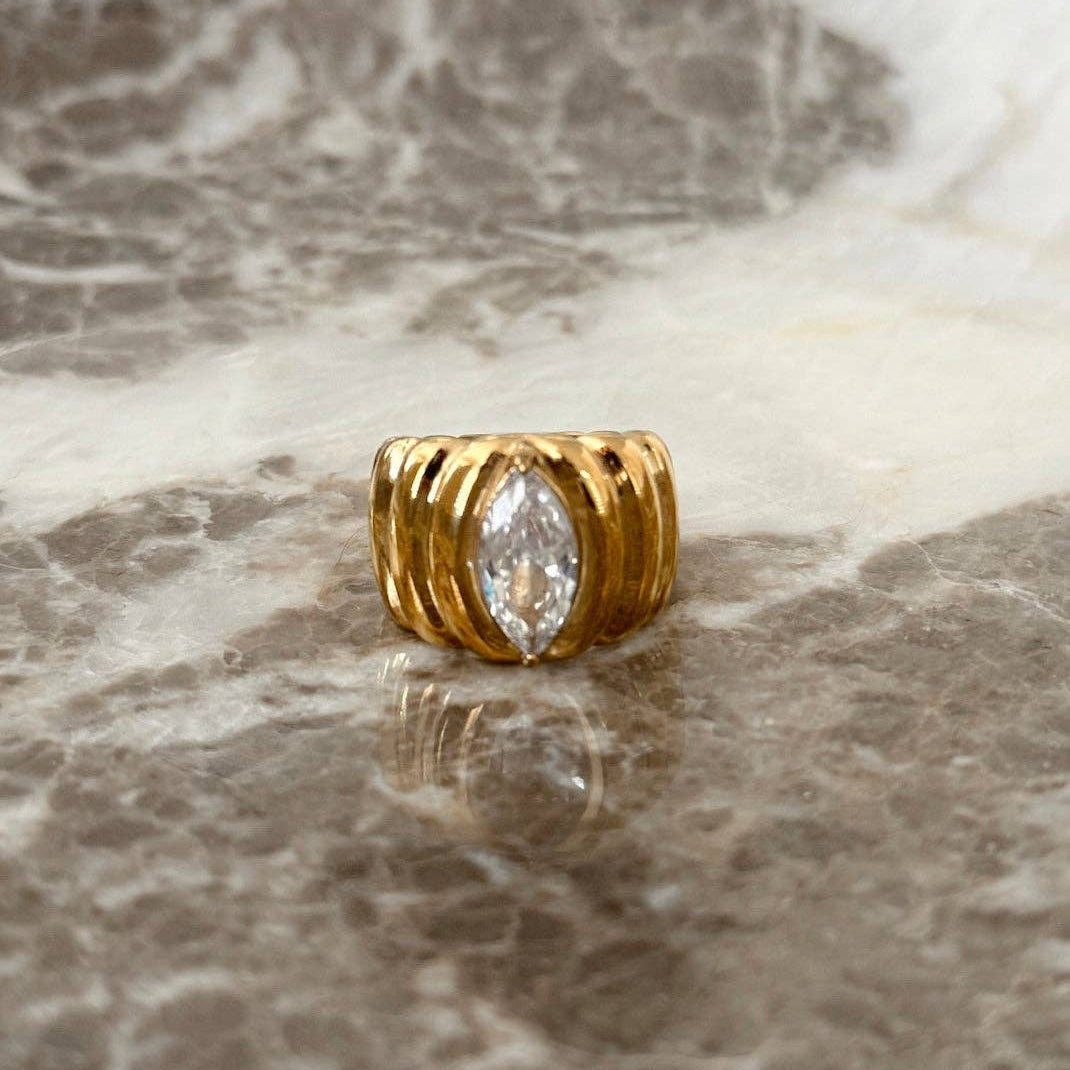 Gold ring with a diamond on a marble surface