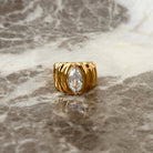 Gold ring with a diamond on a marble surface