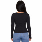 A woman viewed from the back wearing a fitted black long-sleeve top and light blue jeans against a plain white background.