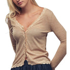 Woman wearing a beige long-sleeve top with lace trim on a white background