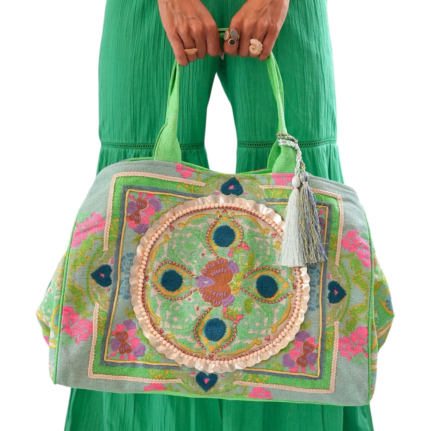 Colorful embroidered handbag held by a person wearing a green dress.