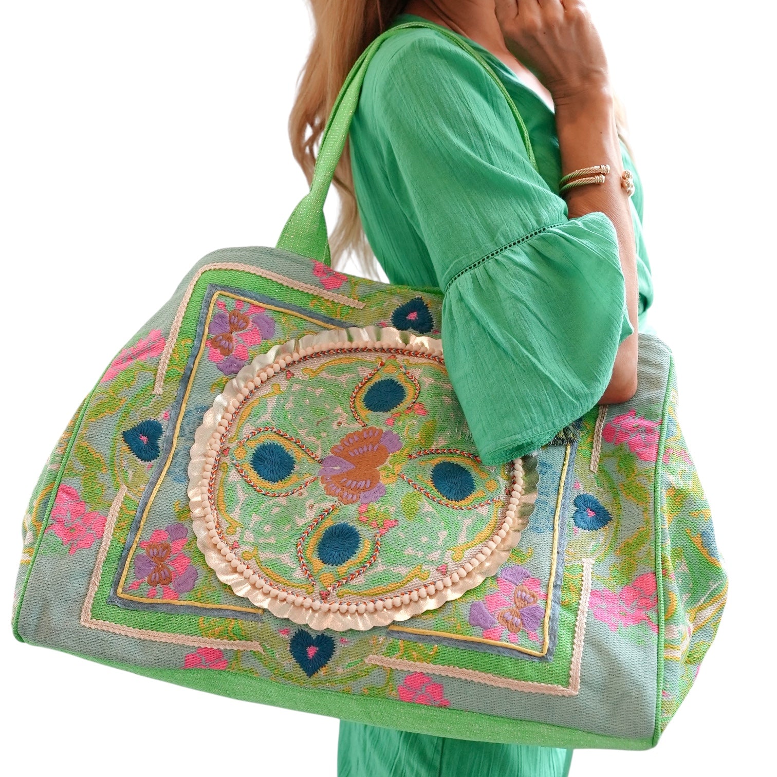 Person holding a decorative handbag with intricate patterns on a white background