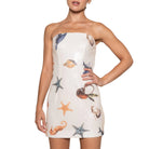 Woman wearing a strapless dress with shell and starfish patterns on a white background