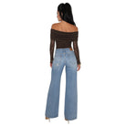 A woman shown from the back wearing a dark brown off-the-shoulder long-sleeve bodysuit with sheer lace sleeves and light-wash blue wide-leg jeans, against a plain white background.