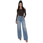 A woman modeling a dark brown off-the-shoulder long-sleeve bodysuit and light-wash distressed wide-leg jeans against a plain white background.