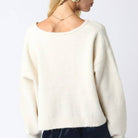 White sweater worn by a person on a plain background