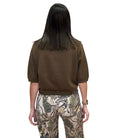 Person wearing a olive shirt and camouflage pants on a white background