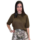 Woman wearing a olive sweater and camouflage pants on a white background