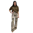 Woman wearing a olive top and camouflage pants on a white background