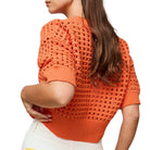Person wearing an orange textured sweater on a white background