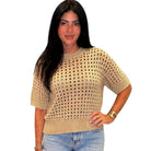 Woman wearing a beige knitted sweater and blue jeans on a white background