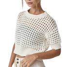White open-knit sweater worn by a person on a white background